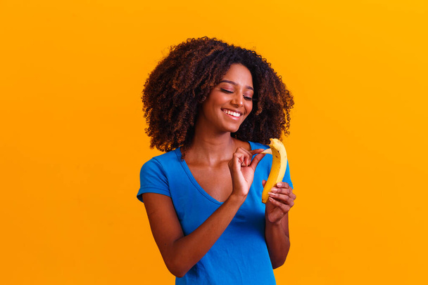 Una joven afro comiendo plátano. Concepto de salud. Alimentación saludable - Foto, Imagen