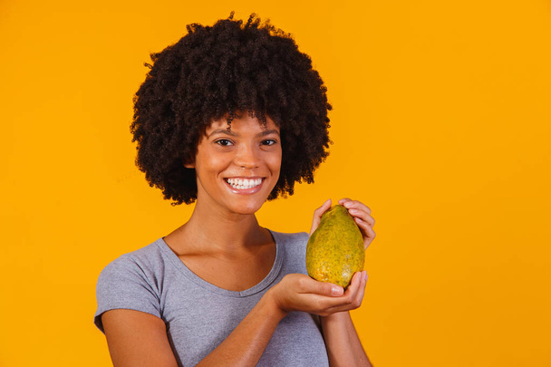 Young beautiful woman holding papaya over yellow isolated background - Foto, Imagem