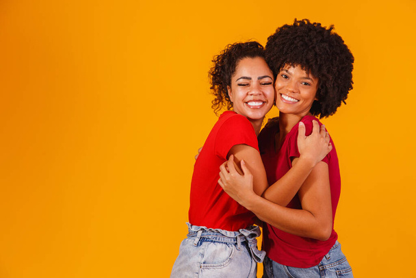 afro lesbian couple on yellow background. homo-affective couple - Фото, изображение