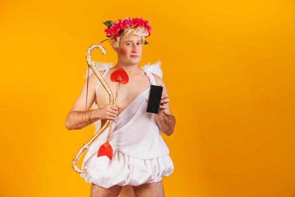 cupid holding cell phone. Valentine's Day promotion - Valokuva, kuva