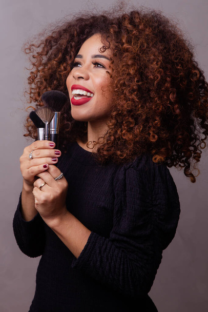 Afro woman professional makeup artist holding makeup brushes. - Fotó, kép