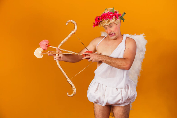 Valentine's day concept. Portrait of the God of love - Cupid with bow and arrow on a yellow background. - Photo, Image