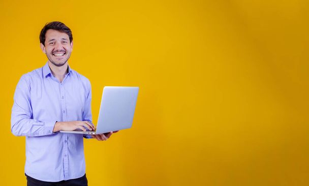 handsome man working with his laptop on yellow background. - Valokuva, kuva