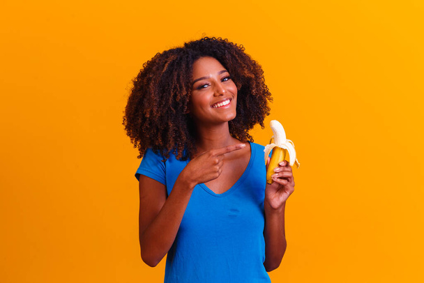 young afro girl eating banana. Health concept. Healthy eating - Foto, afbeelding
