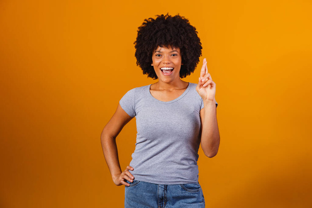 afro woman with fingers crossed cheering victory - Foto, Imagem
