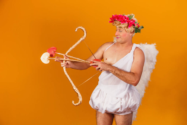 Valentine's day concept. Portrait of the God of love - Cupid with bow and arrow on a yellow background. - Foto, Imagen