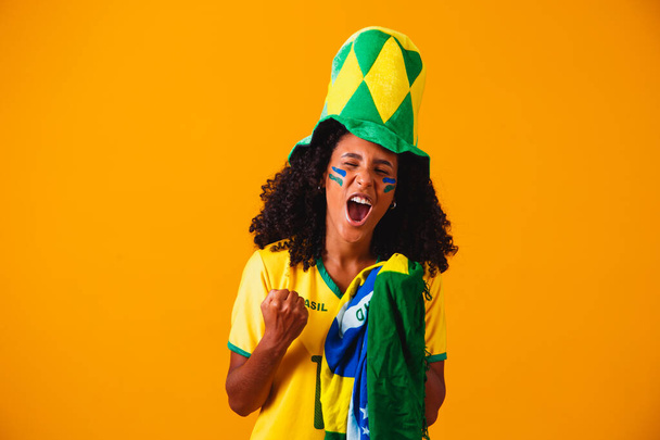Brazilian fan. Brazilian fan celebrating football or soccer game on yellow background. Colors of Brazil. - Photo, image
