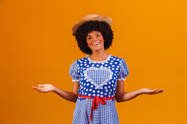 Brazilian afro woman wearing typical clothes for the Festa Junina in yellow background - Fotó, kép