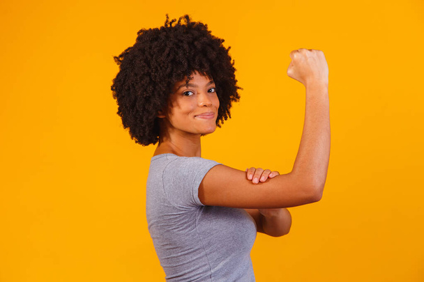 We can do it. Woman's fist of female power. Woman victim of racism. Abuse at work. The feminine power. Female empowerment. The strength of women. Yellow background. - Фото, зображення