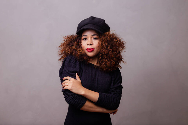 Afro woman with curly hair wearing beret and warm clothes. - Foto, imagen