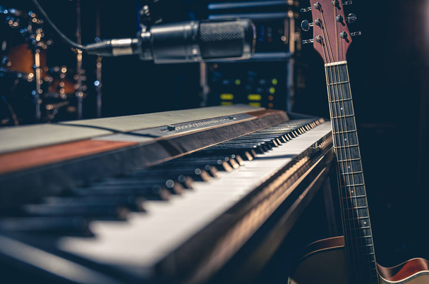 Musical keys, guitar and microphone on a dark background, electronic piano on stage or in a music studio. - Foto, afbeelding