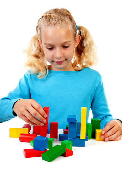 Young blonde girl is playing with colorful wooden blocks - Foto, Imagem