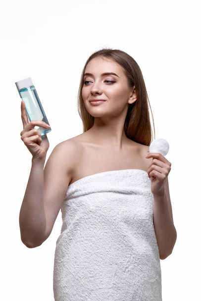 beautiful woman holding bottle with tonic, cleaning skin with cotton pad. Beauty and skin care concept - Фото, изображение