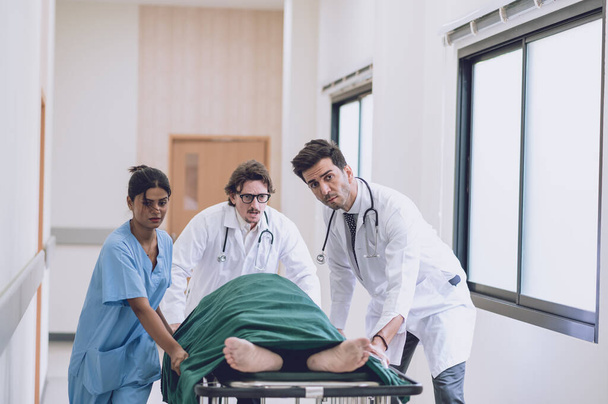Medici, infermieri e paramedici spingono il letto della barella con il paziente gravemente ferito verso la sala operatoria. Personale professionale che salva delle vite. Concetto sanitario - Foto, immagini