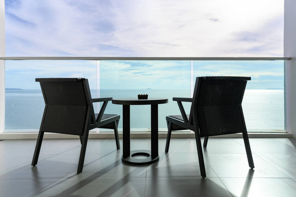 Visszapillantás Két modern rattan fotel, hamutartó az asztalon, tengerre néző kék ég alatt. kilátás az erkélyről. Nyári vakáció. üdülési cél - Fotó, kép