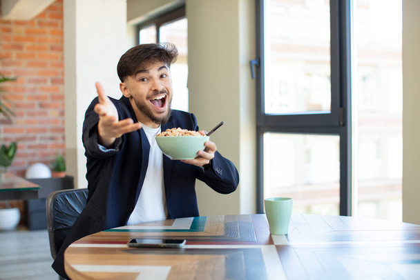 young handsome man smiling happily and offering or showing a concept. breakfast concept - Foto, afbeelding
