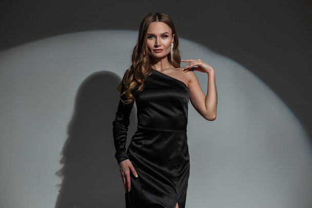 Lovely beautiful glamorous chic woman with a diamond earring in an elegant black stylish evening dress on a dark background at a party. Pretty Lady celebrates an event - Fotografie, Obrázek