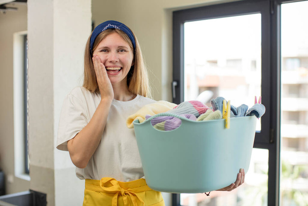 young pretty woman feeling happy and astonished at something unbelievable. laundry and wash clothes concept - Foto, Bild
