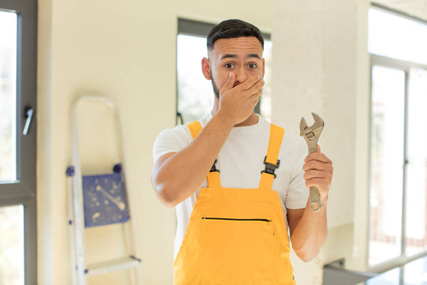arab handsome man arab man covering mouth with a hand and shocked or surprised expression. handyman with a wrench - Foto, Imagen