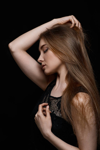 gorgeous brunette woman with long hair in black dress on black background - Foto, imagen