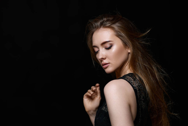 beautiful brunette woman with long hair in black dress on black background. copy space - Foto, Imagem
