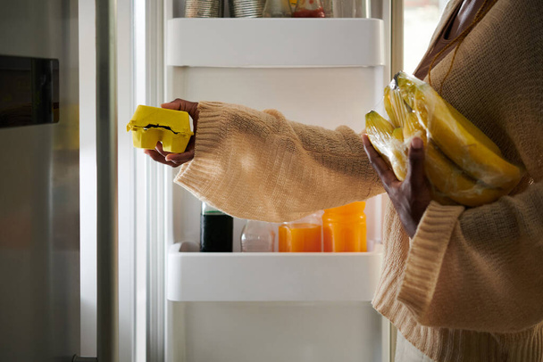 Γυναίκα λαμβάνοντας αυγά και μπανάνες από το ψυγείο για να κάνει πρωινό - Φωτογραφία, εικόνα