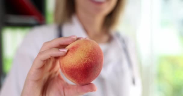 De diëtitische arts houdt perzikfruit in de hand. Gezonde voeding advies en vitamine - Video