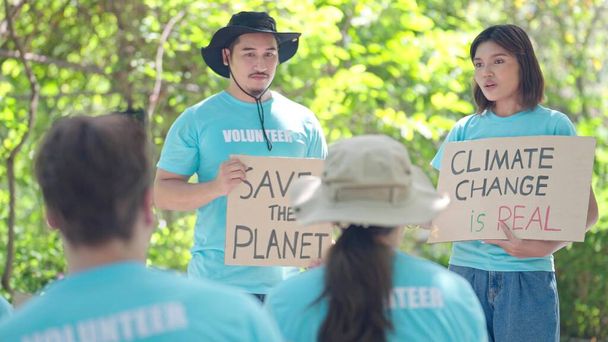 Un jeune homme et une jeune femme asiatiques encourageants pour sauver la planète affiche agitante et concept de changement climatique au camp de bénévoles - Photo, image