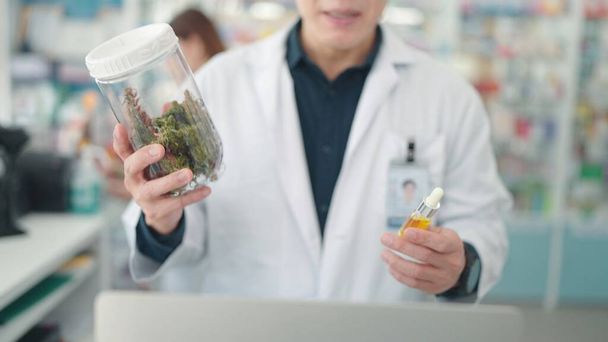 薬局で大麻植物エキスを含む医薬品を保有するアジア系男性薬剤師 - 写真・画像