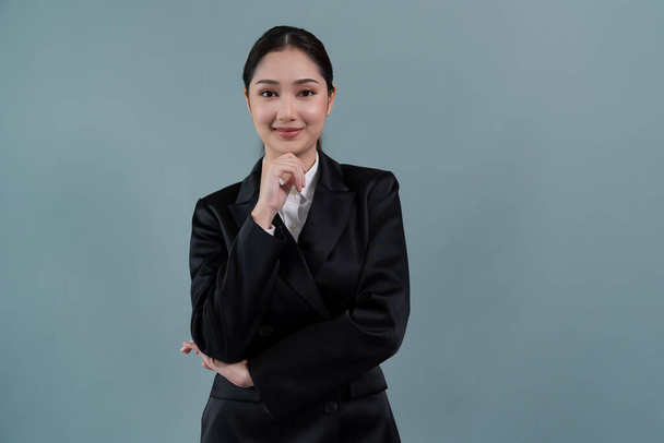 Une jeune femme d'affaires confiante se tient sur un fond isolé, posant en costume noir formel. Dame de bureau ou gestionnaire avec une apparence intelligente et professionnelle. Enthousiaste - Photo, image