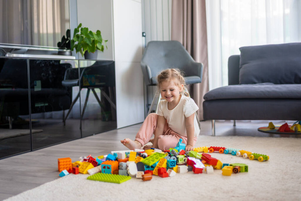 Little girl play with constructor toy on floor in home, educational game, spending leisure activities time concept. High quality photo - Zdjęcie, obraz