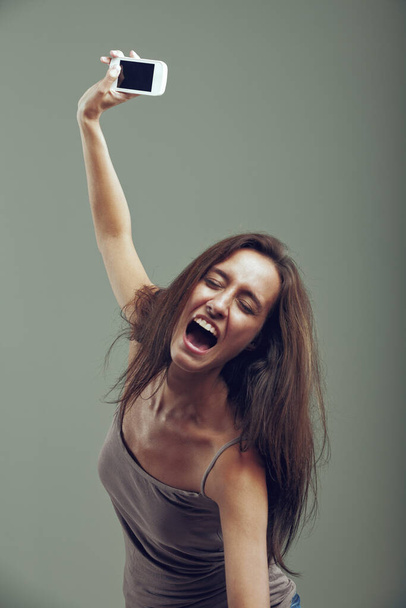 С атлетическим прыжком женщина выбрасывает свой мобильный телефон. Возрожденная гневом, она обладает сильной силой и сопровождает этот жест яростным криком. С неё хватит.! - Фото, изображение