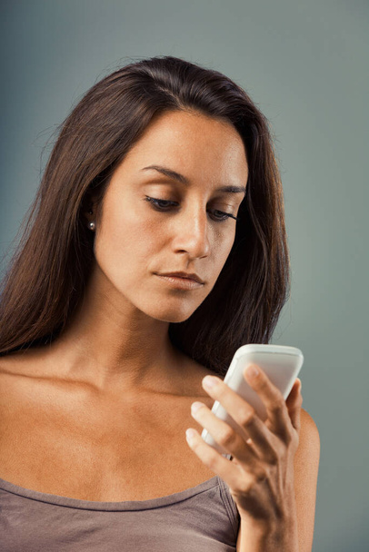 Komoly, zaklatott nő figyeli a mobiltelefon képernyőjét. A düh határán, féken tartja a dühöt. Rossz hírek, bejövő problémák. Lehetséges telefonhiba - Fotó, kép