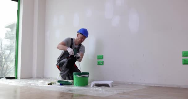 Builder painter stirs building mixture in bucket. Construction worker mixes paint in construction bucket - Footage, Video