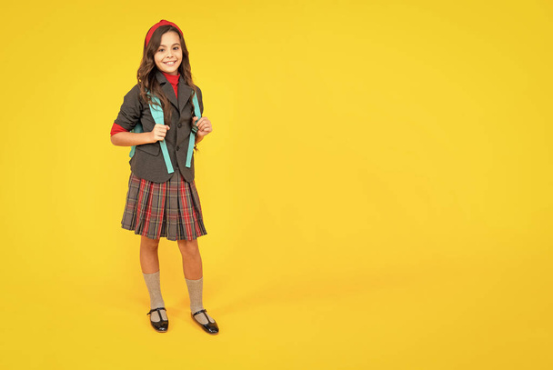happy child in school uniform with backpack on yellow background, copy space, school. - Foto, imagen