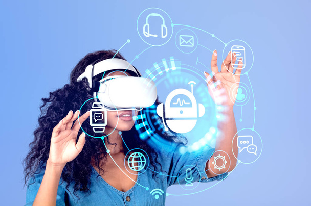 Black young woman working in vr glasses, hands touching chat bot hologram on purple background, social network in metaverse. Concept of artificial intelligence - Photo, image