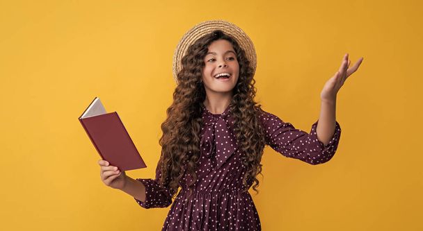 positive child with frizz hair recite book on yellow background. - Foto, Imagem