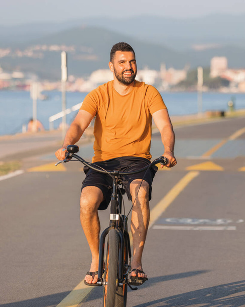 Carefree man with bicycle riding at sunset having fun and smiling - Fotó, kép
