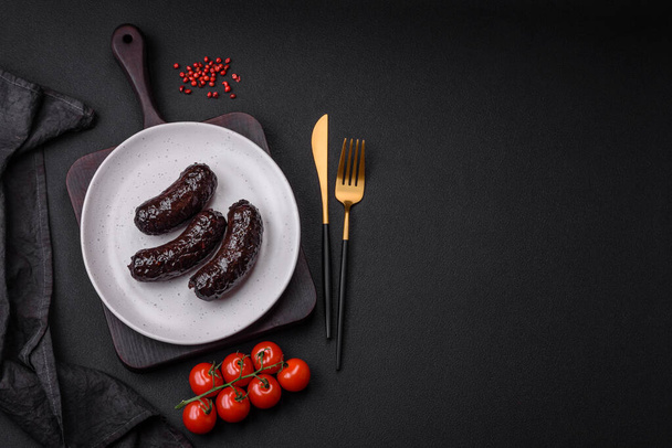 Вкусная черная кровяная колбаса или черный пудинг со специями и травами на черном бетонном фоне - Фото, изображение
