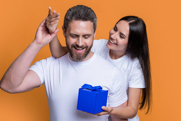 photo of amazed couple with present for holiday surprise. mens day. couple with surprise present isolated on yellow background. surprise couple with present in studio. holiday couple with present box. - Zdjęcie, obraz