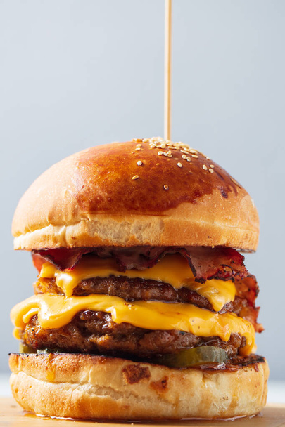 Burger. Double cutlet, double cheddar cheese, bacon, deep-fried onions, pickles, sauce and craft bun. High quality photo - Foto, Imagem