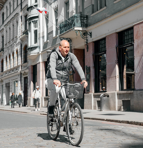 Ljubljana, Szlovénia - 2023 Április 4: Egy jóképű hipszter férfi portréja. Egy férfi egy nagyvárosban az utcán egy kerékpárral, egy életstílus koncepció - Fotó, kép