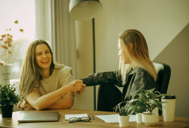 Friendly female colleagues having good relationships, pleasant conversation at workplace during coffee break, smiling young woman listen talkative coworker, discussing new project, talking in office - Foto, Imagen