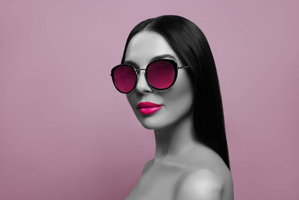 Attractive woman in stylish sunglasses on pink background. Color accent - Foto, Bild