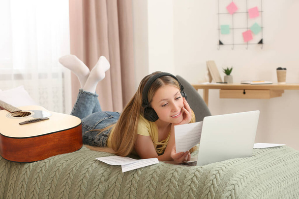 Teenage girl with headphones reading on bed at home - Foto, Bild
