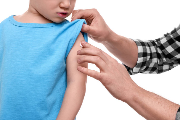 Father applying ointment onto her son`s shoulder on white background, closeup - Zdjęcie, obraz