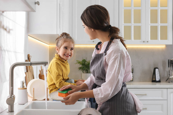 Young mother and her daughter spending time together in kitchen - Valokuva, kuva