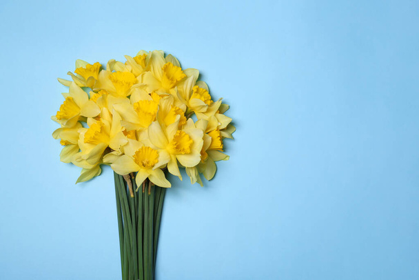 Bouquet of beautiful yellow daffodils on light blue background, top view. Space for text - Фото, изображение