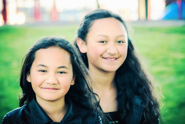 Portrait of two young Maori sisters taken outdoors in a park. - Photo, Image