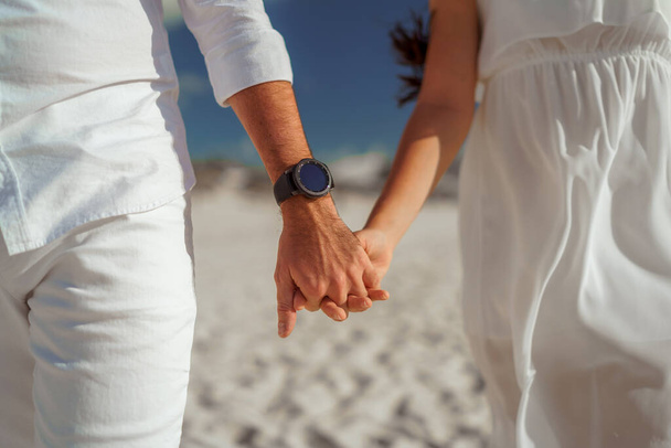 Man en vrouw, pasgetrouwden hand in hand met wazige achtergrond close-up. - Foto, afbeelding